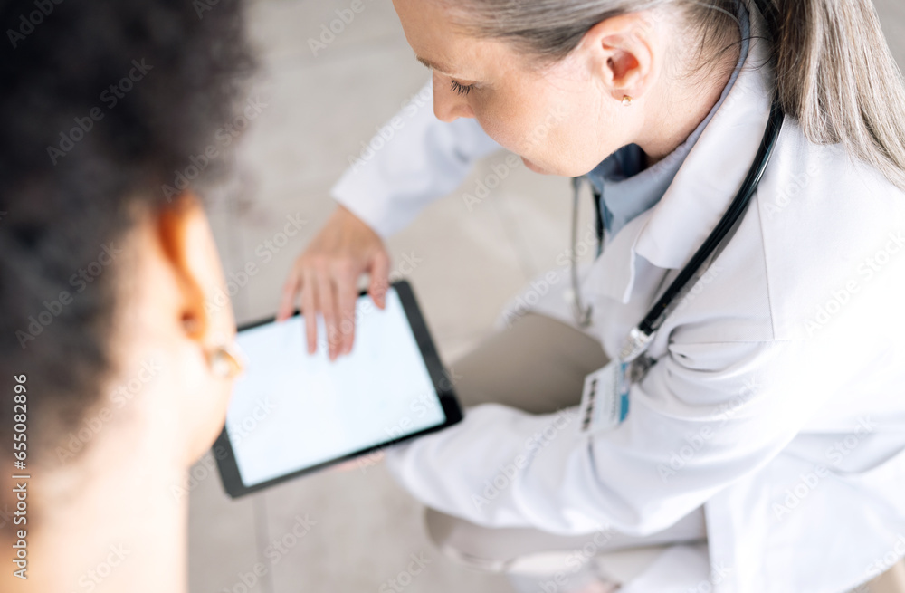 Woman doctor, medical results and tablet screen at hospital with patient and mockup space. Wellness advice, technology and mature female professional with healthcare, consulting and internet search