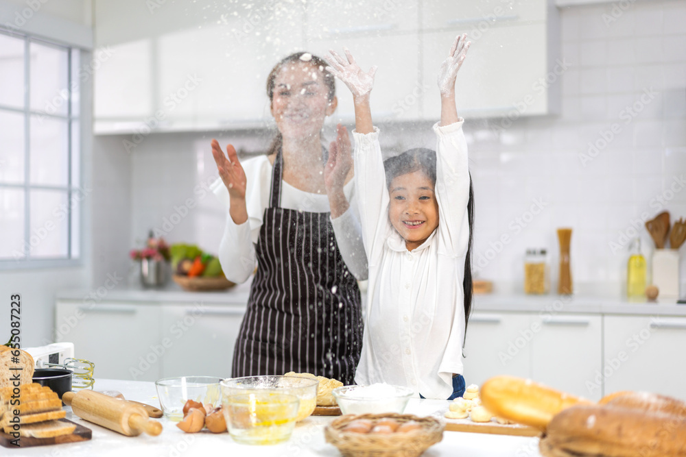 Portrait of enjoy happy love asian family mother and little toddler asian girl daughter child having fun cooking together with dough for homemade bake cookie and cake ingredient on table in kitchen