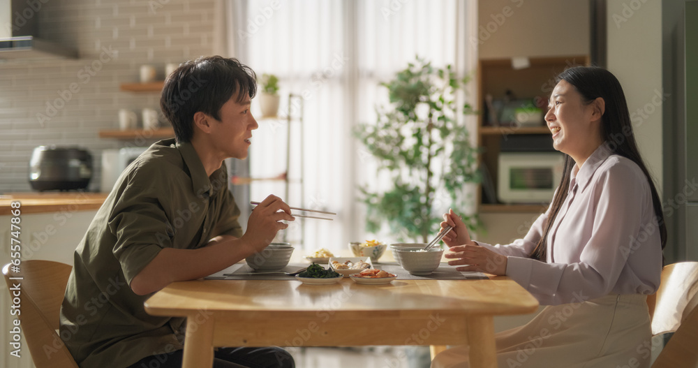 Excited South Korean Boyfriend Meeting His Girlfriend After a Long Trip. Happy Asian Couple Reunite, Hug Each Other at Home Spin and Fall Down on a Comfortable Sofa in a Stylish Living Room