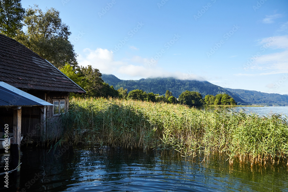 Lake Ossiacher See, Ossiach, Carinthia, Austria. Beautiful summer mountain landscape. Alpine lake surrounded by mountains, slopes of which are covered with forest and white clouds