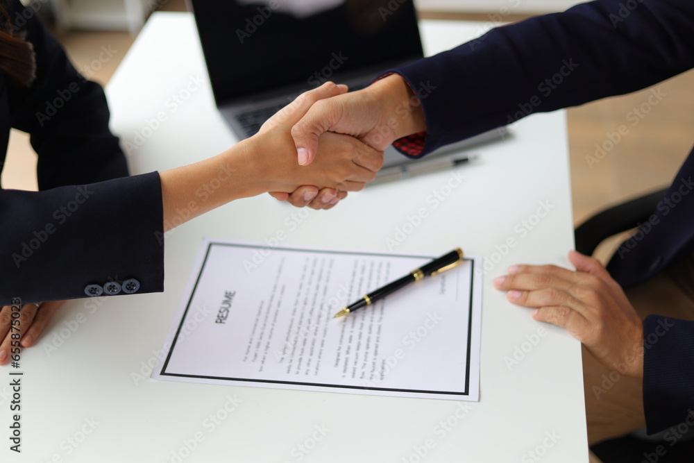 Business partners and colleagues shaking hands at work cooperation. Job applicant shaking hands with executives in office room at job interview.