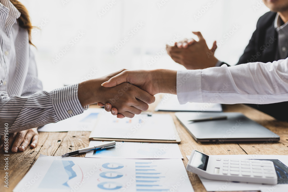 Businesswoman shaking hands with financial advisor at meeting in office.