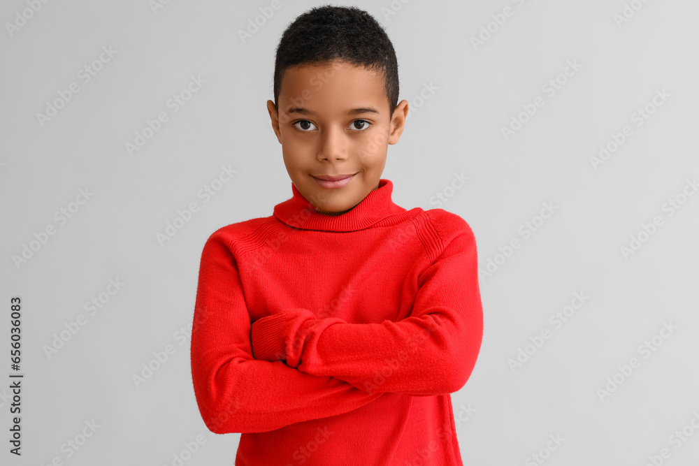 Cute African-American boy in warm sweater on light background