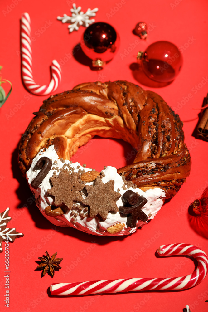 Tasty Christmas pastry wreath, candy canes and decorations on red background