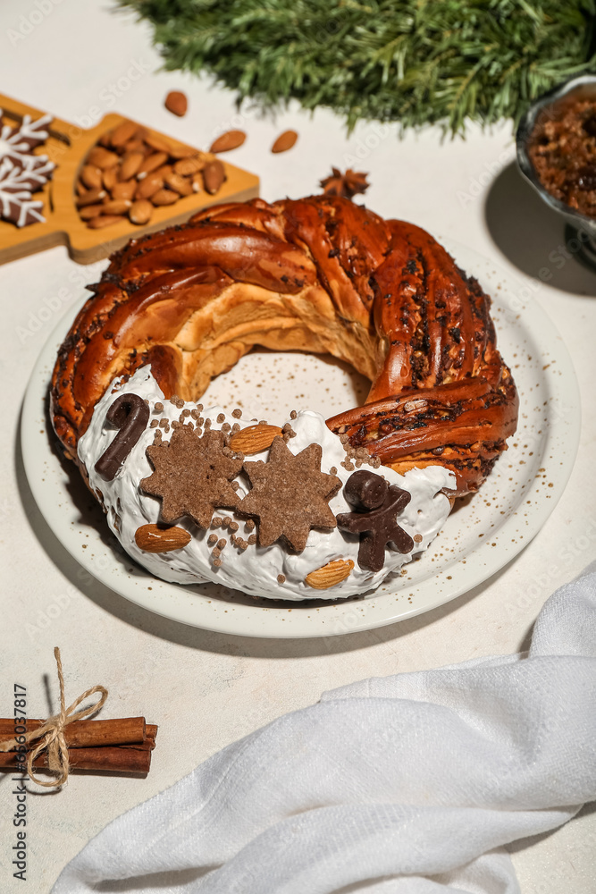 Plate with tasty Christmas pastry wreath on light background