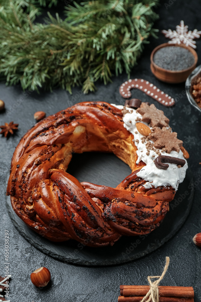 Board with tasty Christmas pastry wreath on dark background, closeup