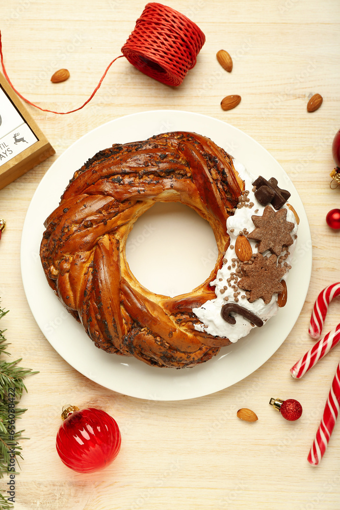 Plate with tasty Christmas pastry wreath and decorations on wooden background