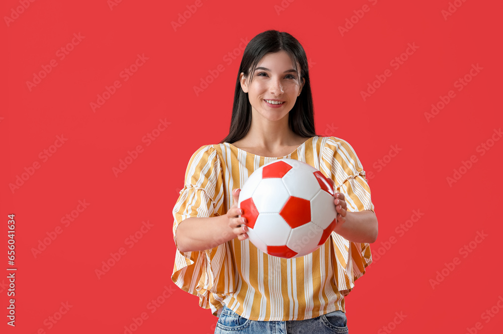 Happy young woman with soccer ball on red background