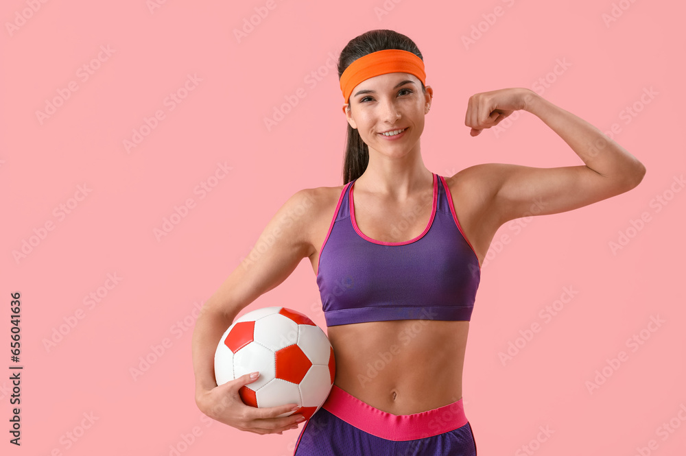 Sporty young woman with soccer ball on pink background