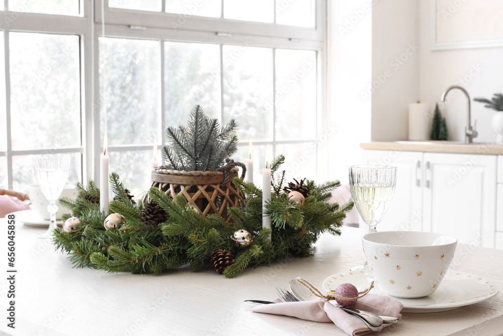 White dining table with champagne glasses, burning candles and Christmas wreath in kitchen