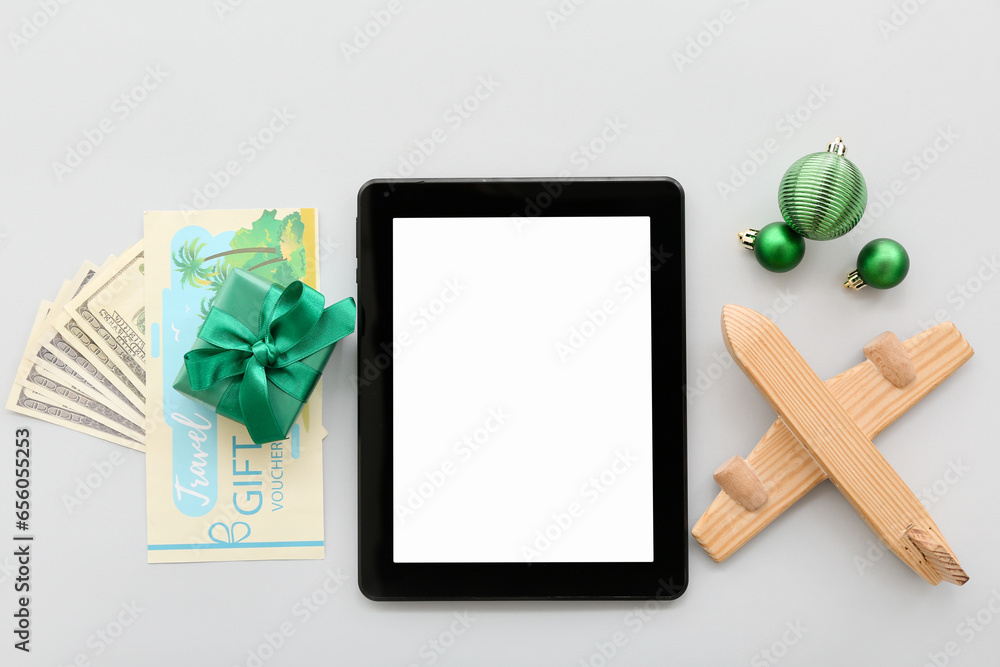 Tablet computer with wooden airplane and Christmas decor on light background