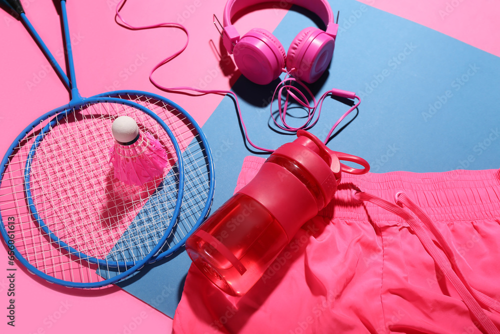 Composition with bottle of water, headphones, badminton rackets and shuttlecock on color background