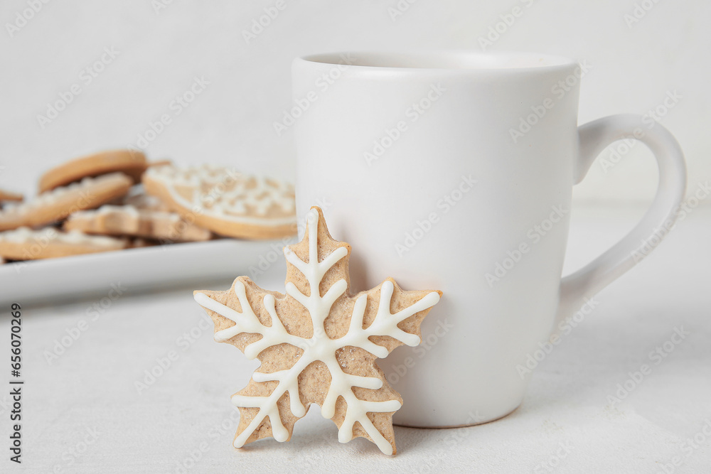 Tasty Christmas cookie and cup of drink on light background