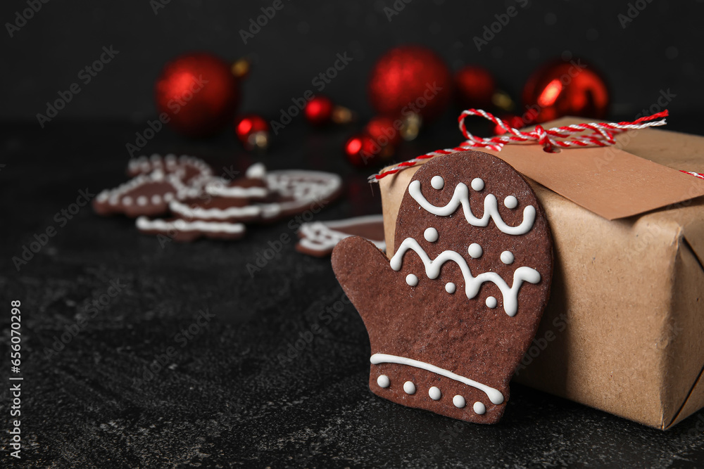 Tasty Christmas cookie and gift box on dark background