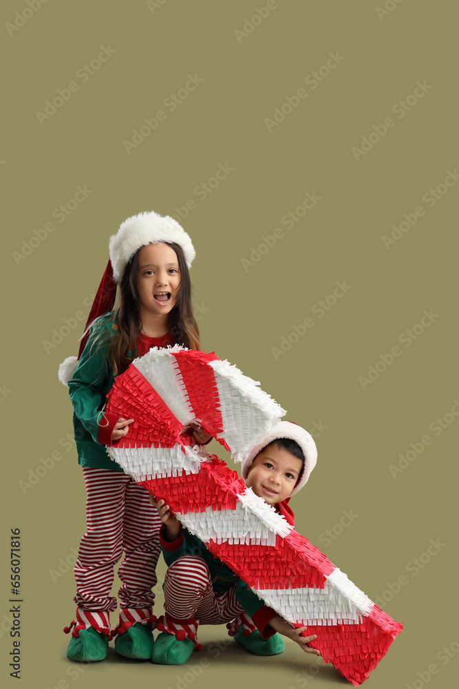 Cute little children in elfs costumes and with Christmas pinata on green background