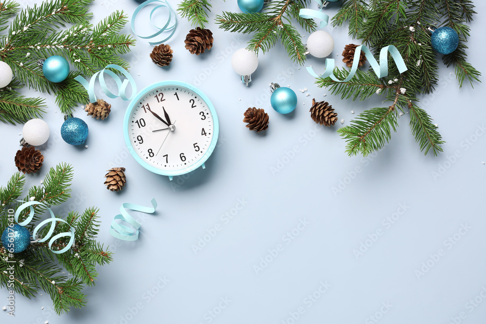 Alarm clock and Christmas tree branches with balls on blue background