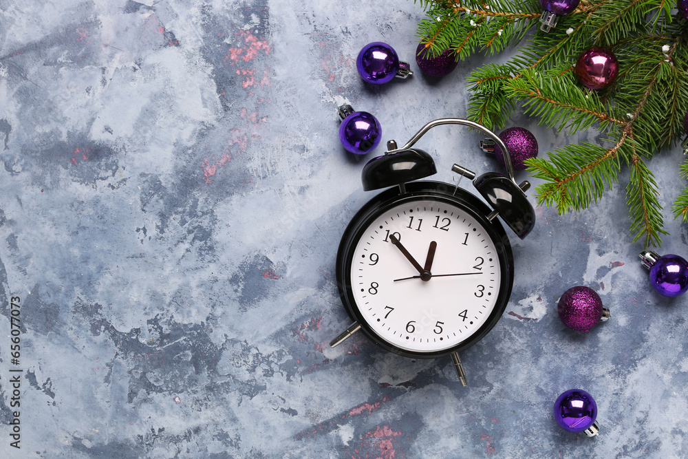 Alarm clock and Christmas tree branches with balls on blue background