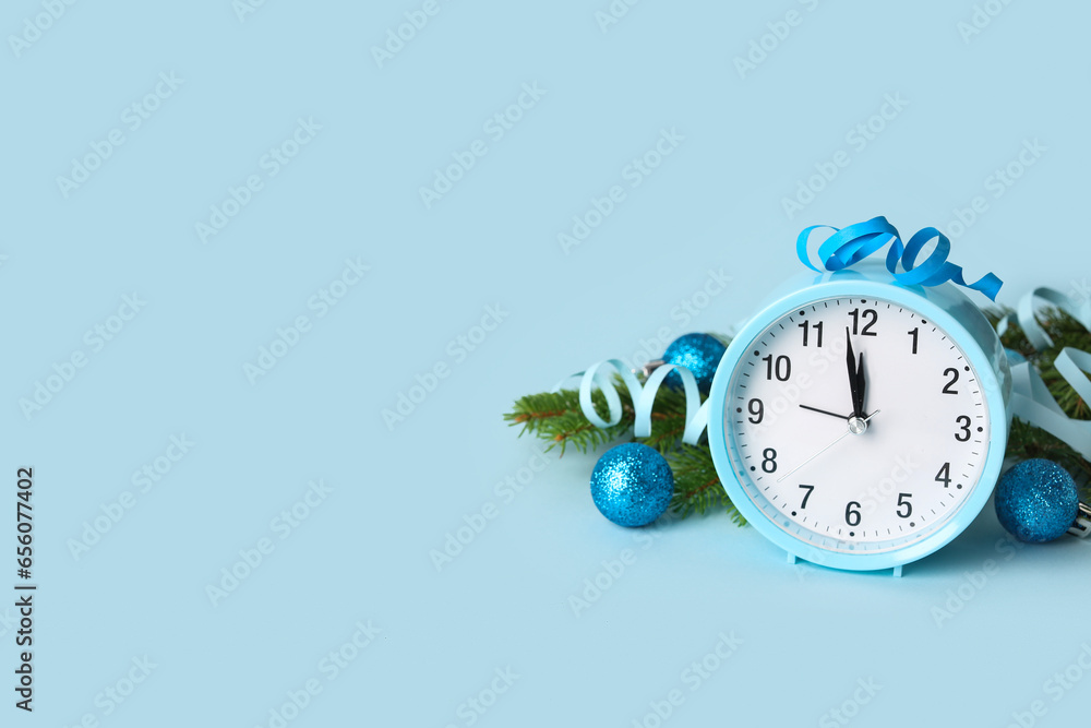 Alarm clock and Christmas tree branches with balls on blue background