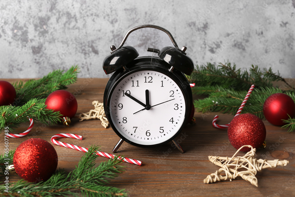 Alarm clock and Christmas tree branches with balls on wooden table