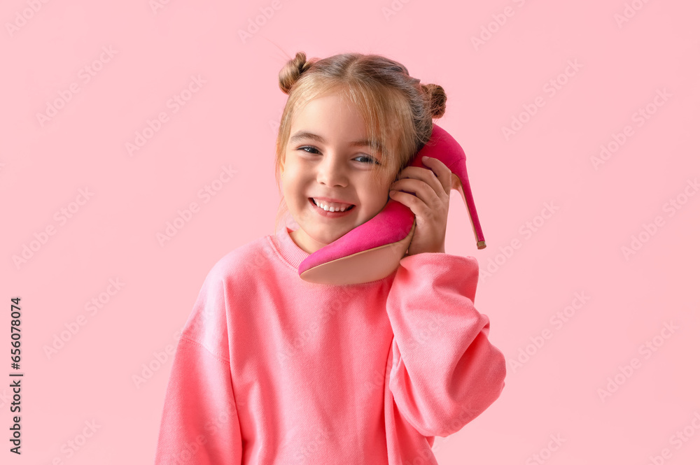 Cute little girl with heel on pink background