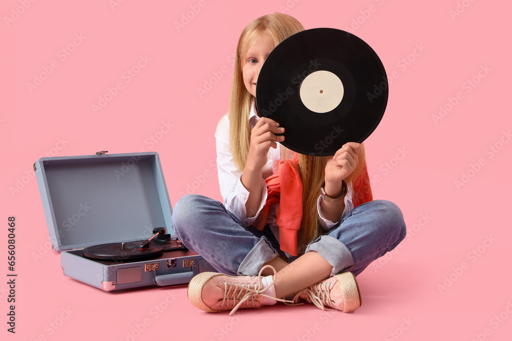 Little girl with vinyl disk and record player on pink background