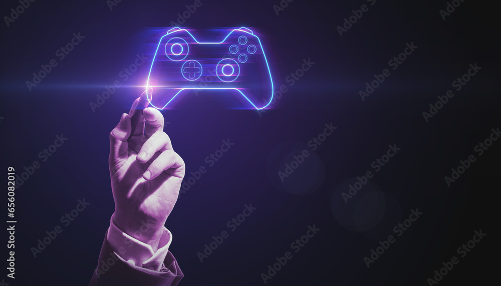 Closeup of business man hand pointing at creative joystick or gamepad hologram on blurry purple bokeh background. Esport, gaming and fun concept.