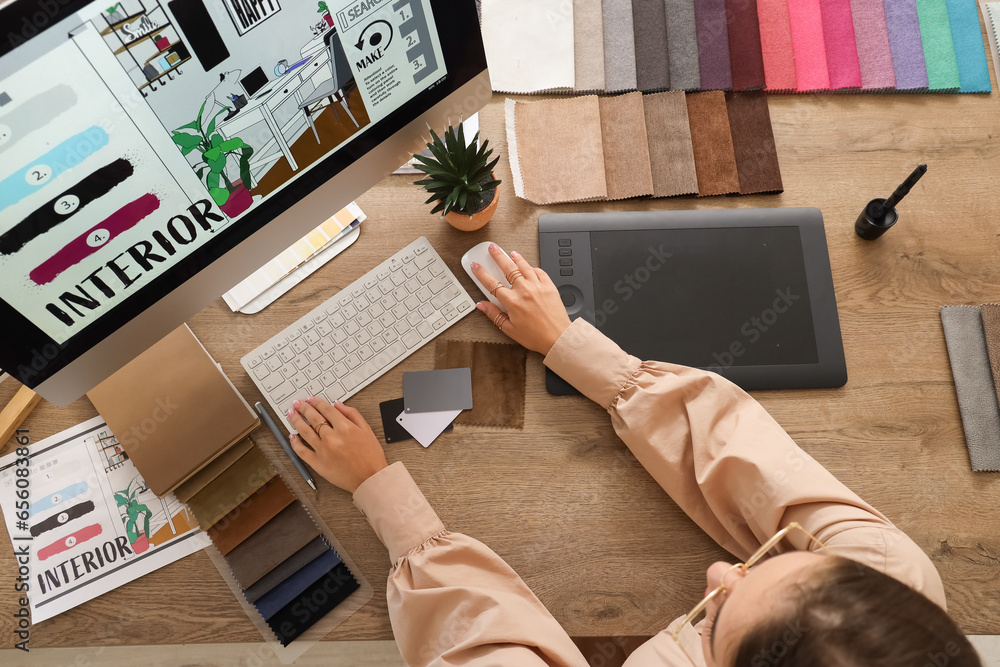 Female interior designer working with computer at table in office, top view