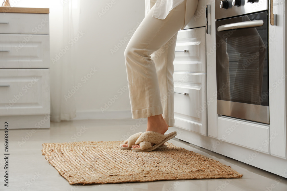 Woman on wicker carpet in light kitchen