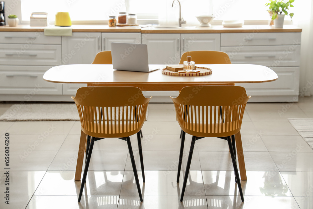 Interior of light kitchen with white counters and dining table