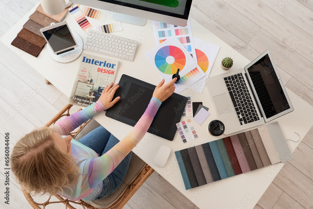 Female interior designer working with graphic tablet at table in office, top view