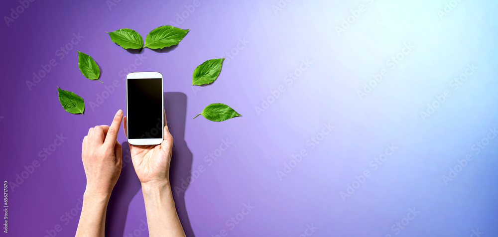 Person holding a smartphone with green leaves