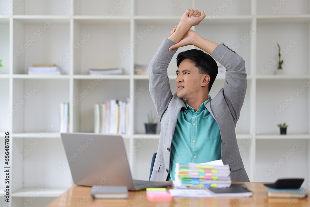 A aches businessman stretching to relax after working in the office.