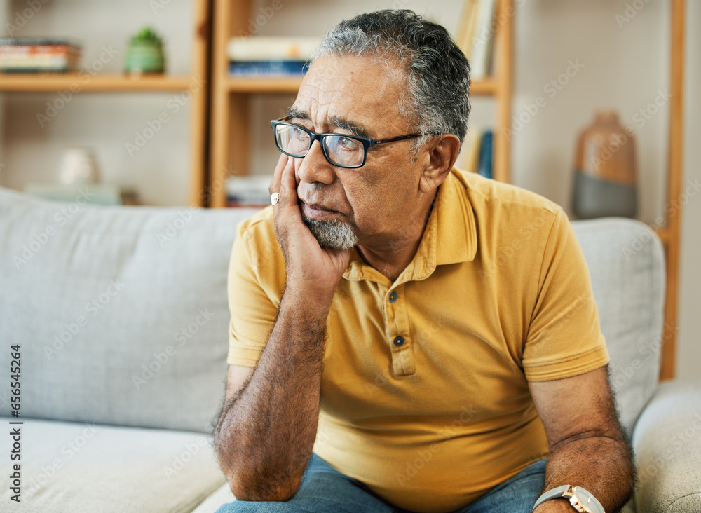 Face, depression and alzheimer with a sad old man on a sofa in the living room of his retirement home. Mental health, thinking or dementia and a senior person looking lonely with memory nostalgia