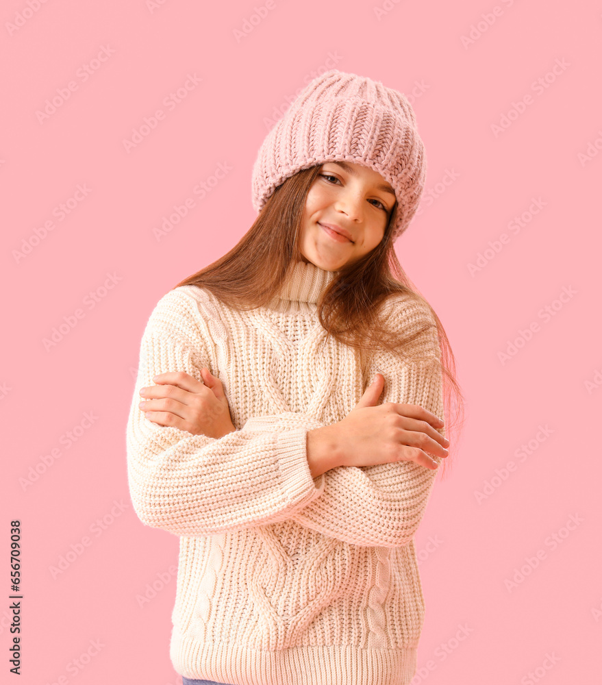 Cute little girl in winter clothes on pink background