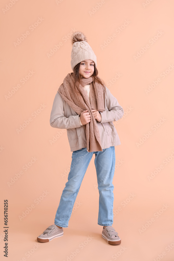 Cute little girl in winter clothes on beige background