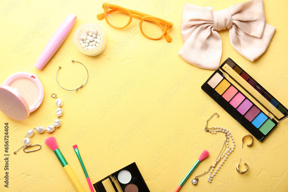 Frame made of stylish female accessories and cosmetics on yellow background