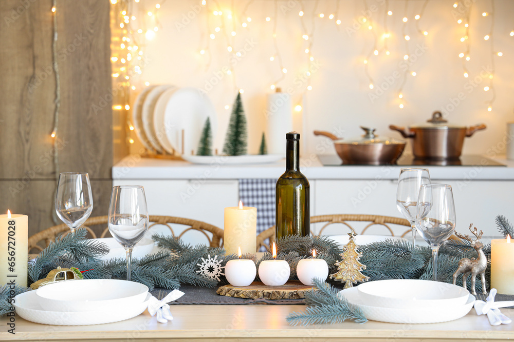 Beautiful table setting with Christmas decorations and burning candles in festive kitchen