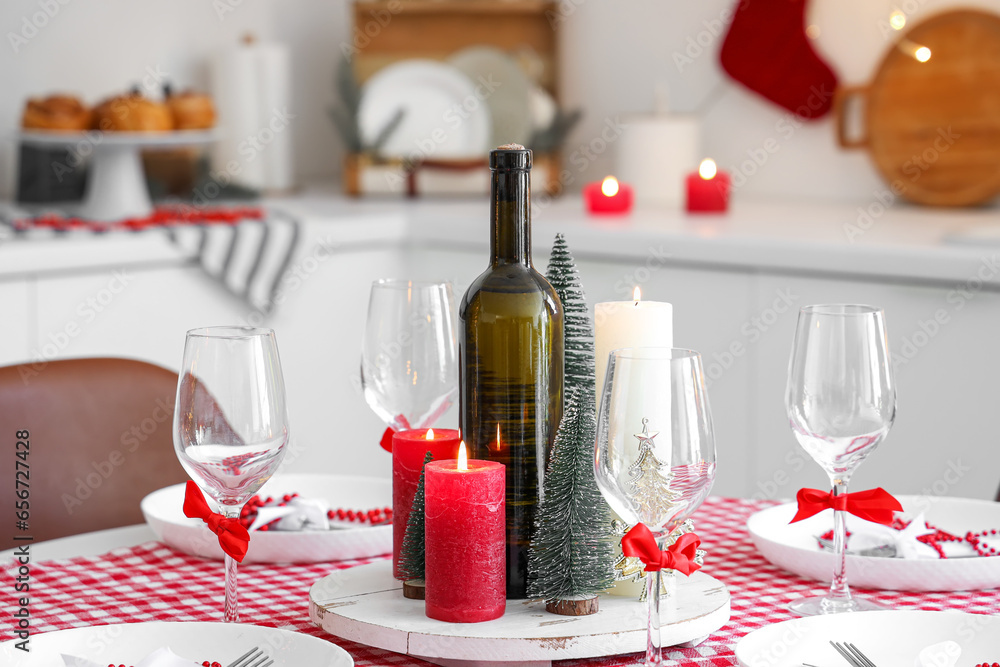 Beautiful table setting with Christmas decorations and burning candles in festive kitchen