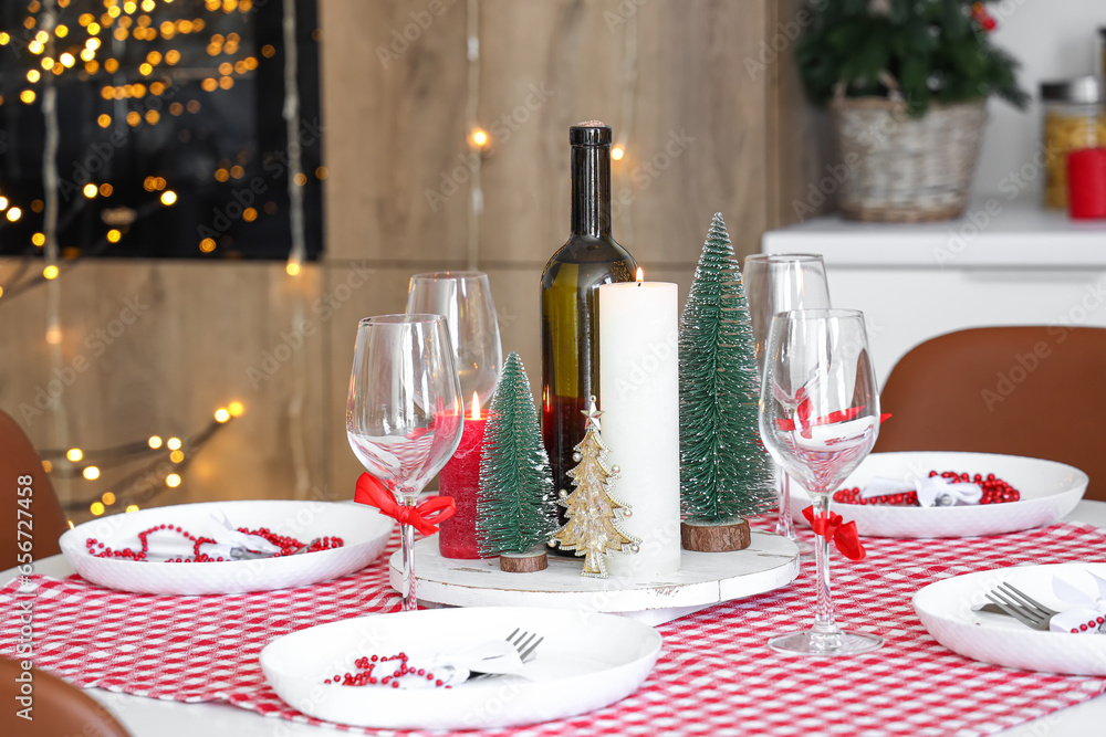 Beautiful table setting with Christmas decorations and burning candles in festive kitchen