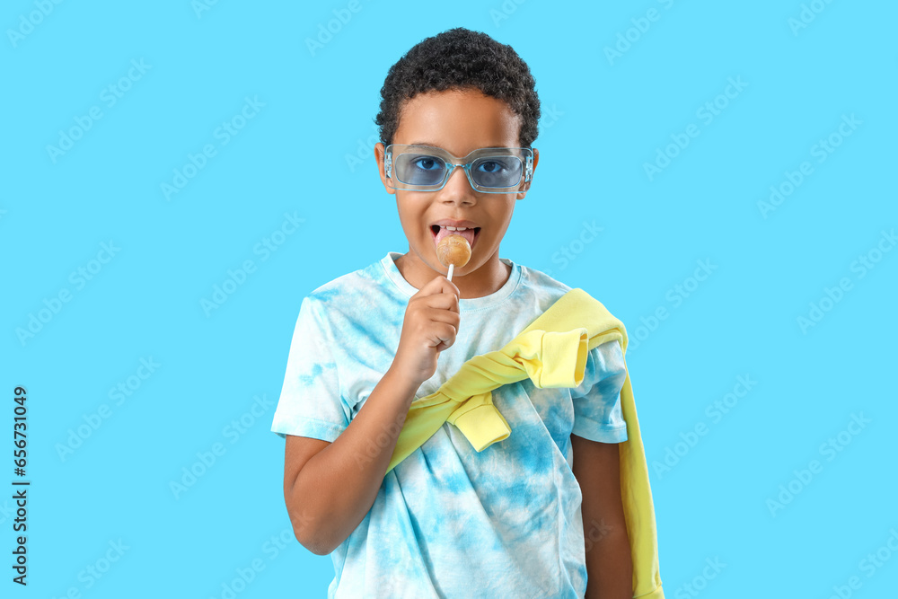 African-American little boy with lollipop on blue background