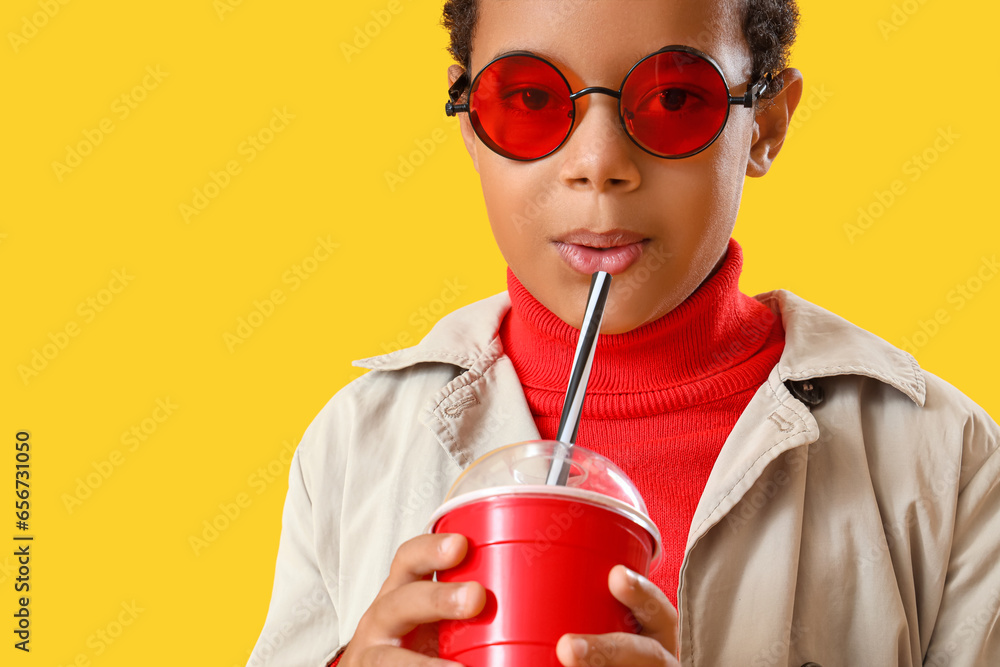 African-American little boy in sunglasses with soda on yellow background, closeup