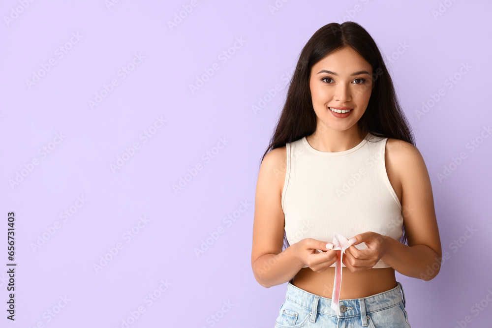 Beautiful young Asian woman with wax strip on lilac background