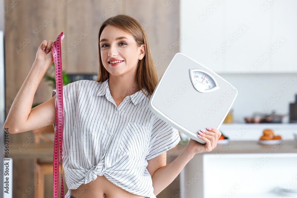 Beautiful young woman with measuring tape and scales in kitchen. Weight loss concept