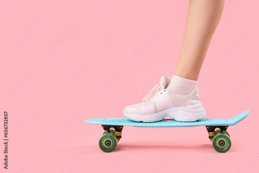 Young woman with skateboard on pink background, closeup