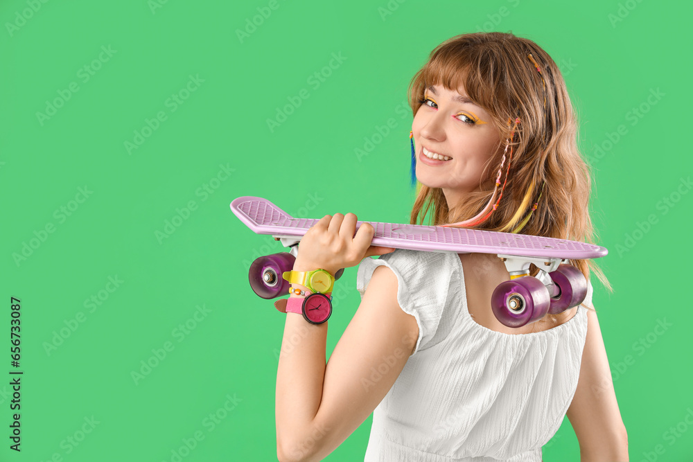 Young woman with skateboard on green background