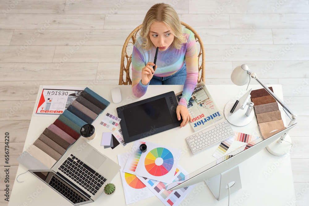 Female interior designer working with graphic tablet at table in office, top view