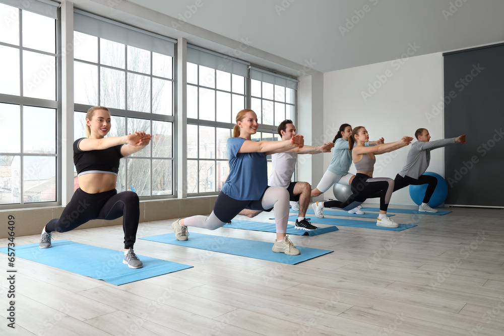 Group of sporty young people stretching in gym