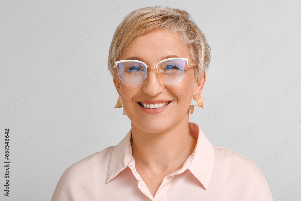 Mature blonde woman in eyeglasses on light background, closeup