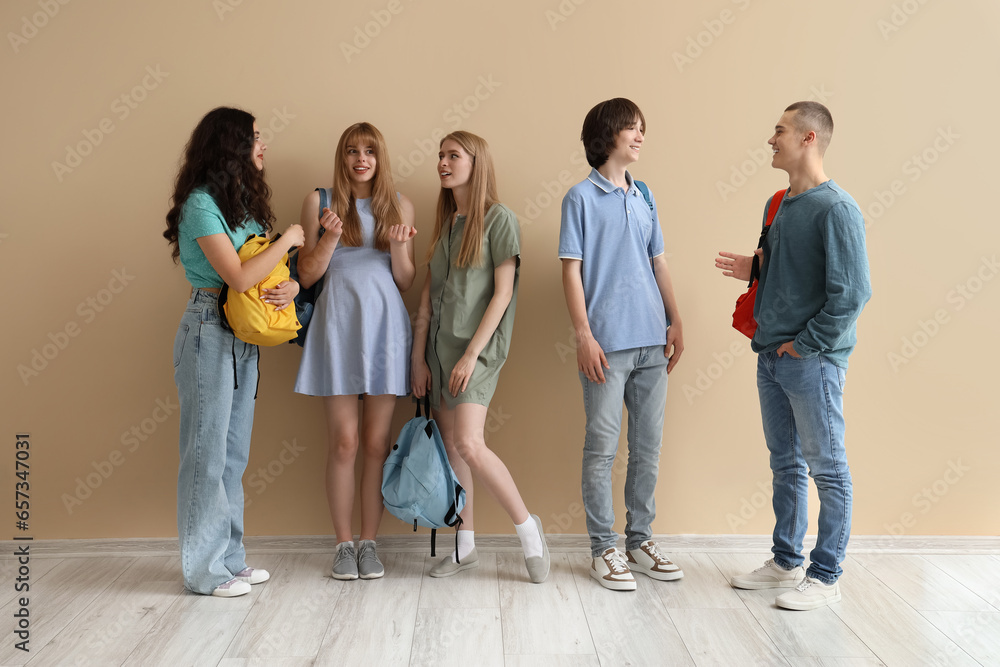 Group of students with backpacks near beige wall