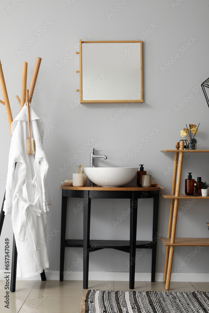 Interior of bathroom with shelving unit, sink bowl and bath accessories on table